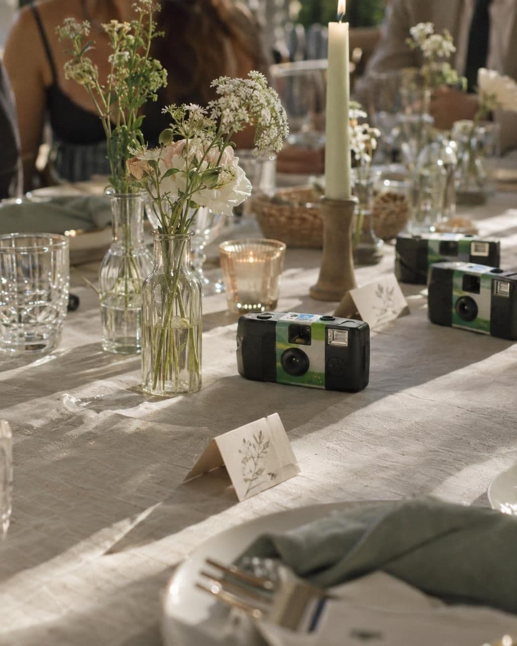 Disposable cameras lined up on a wedding table among bud vases